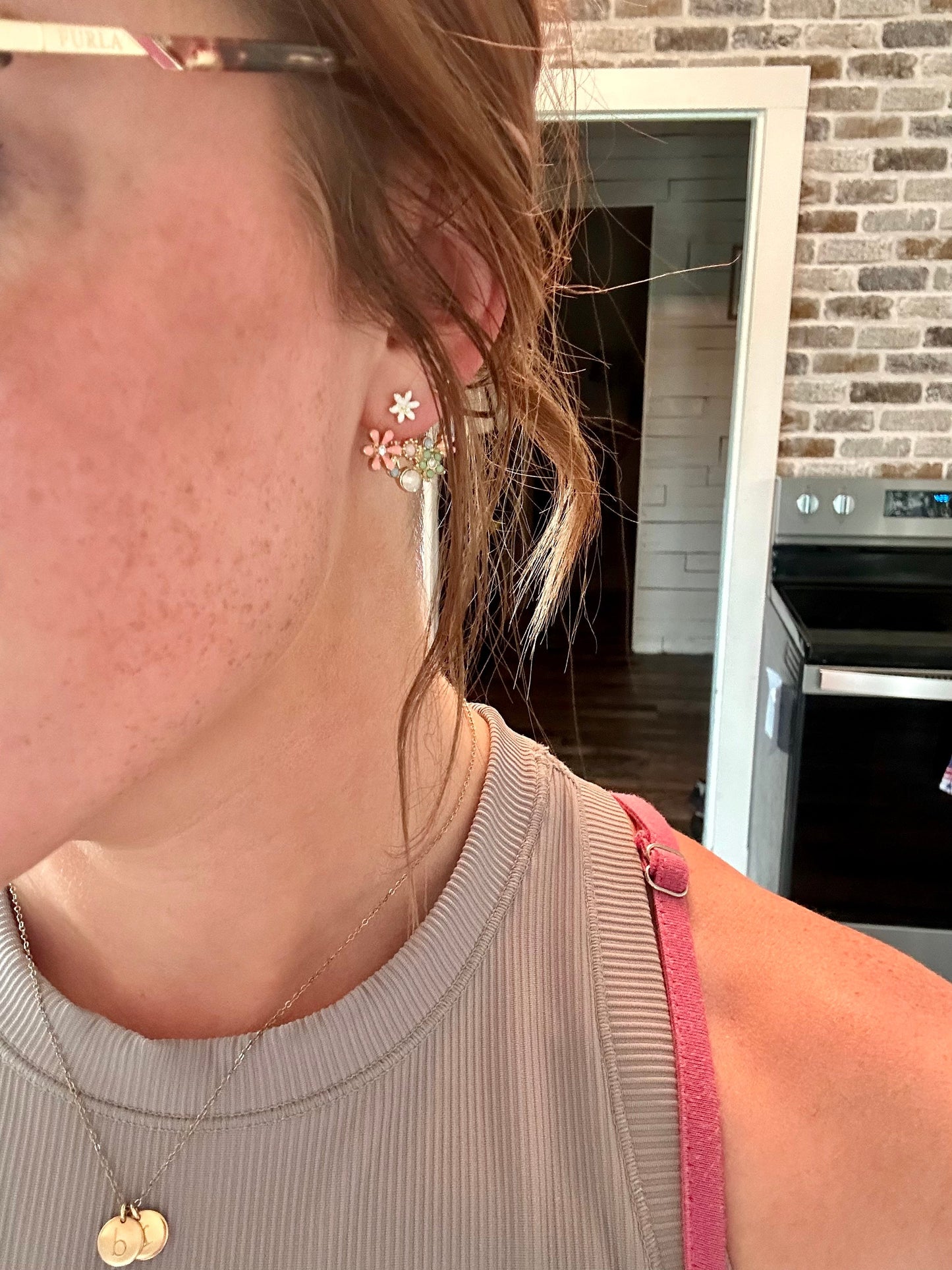 Close-up of a person wearing floral earrings with a kitchen background