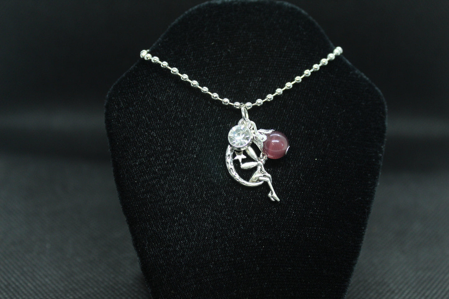 silver necklace with pendant on a black velvet stand
