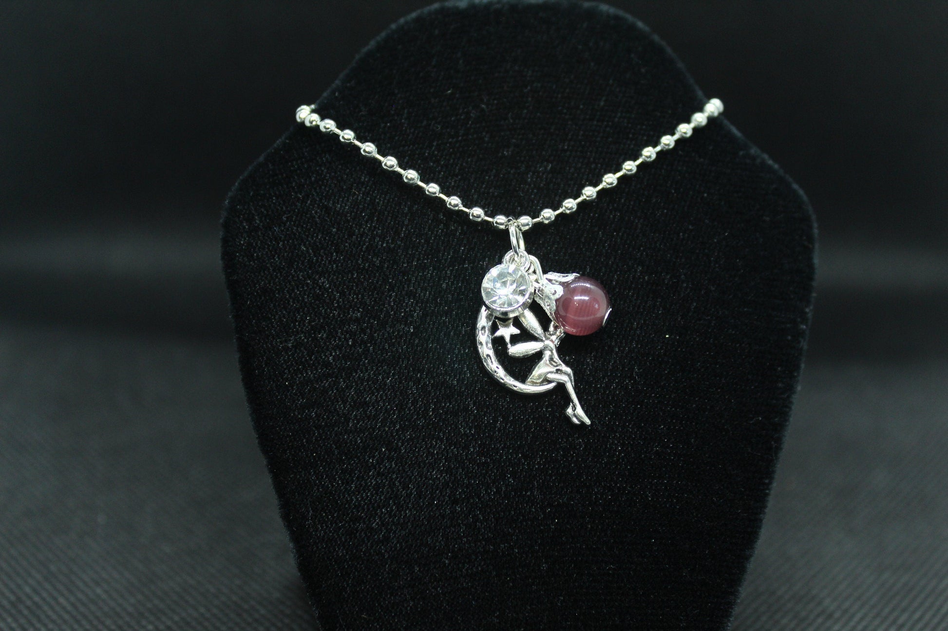 silver necklace with pendant on a black velvet stand