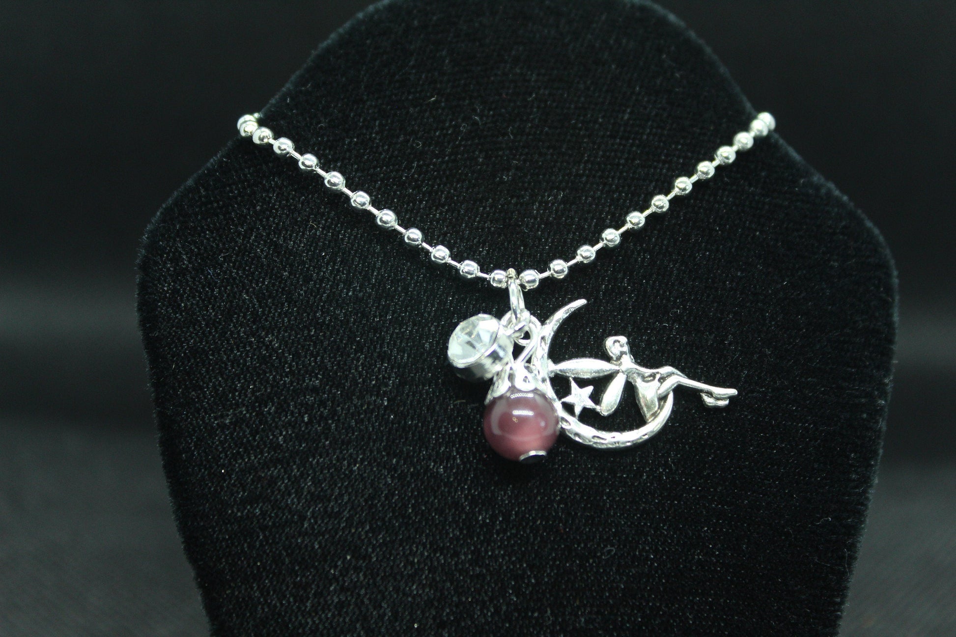 silver necklace with pendant on a black velvet stand