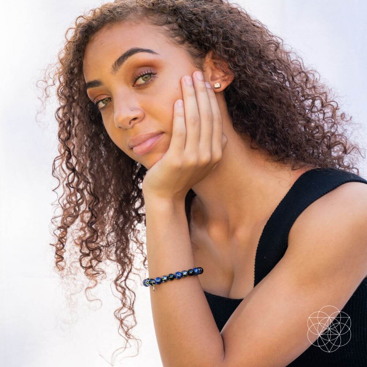 Woman with curly hair wearing a black top against a light background