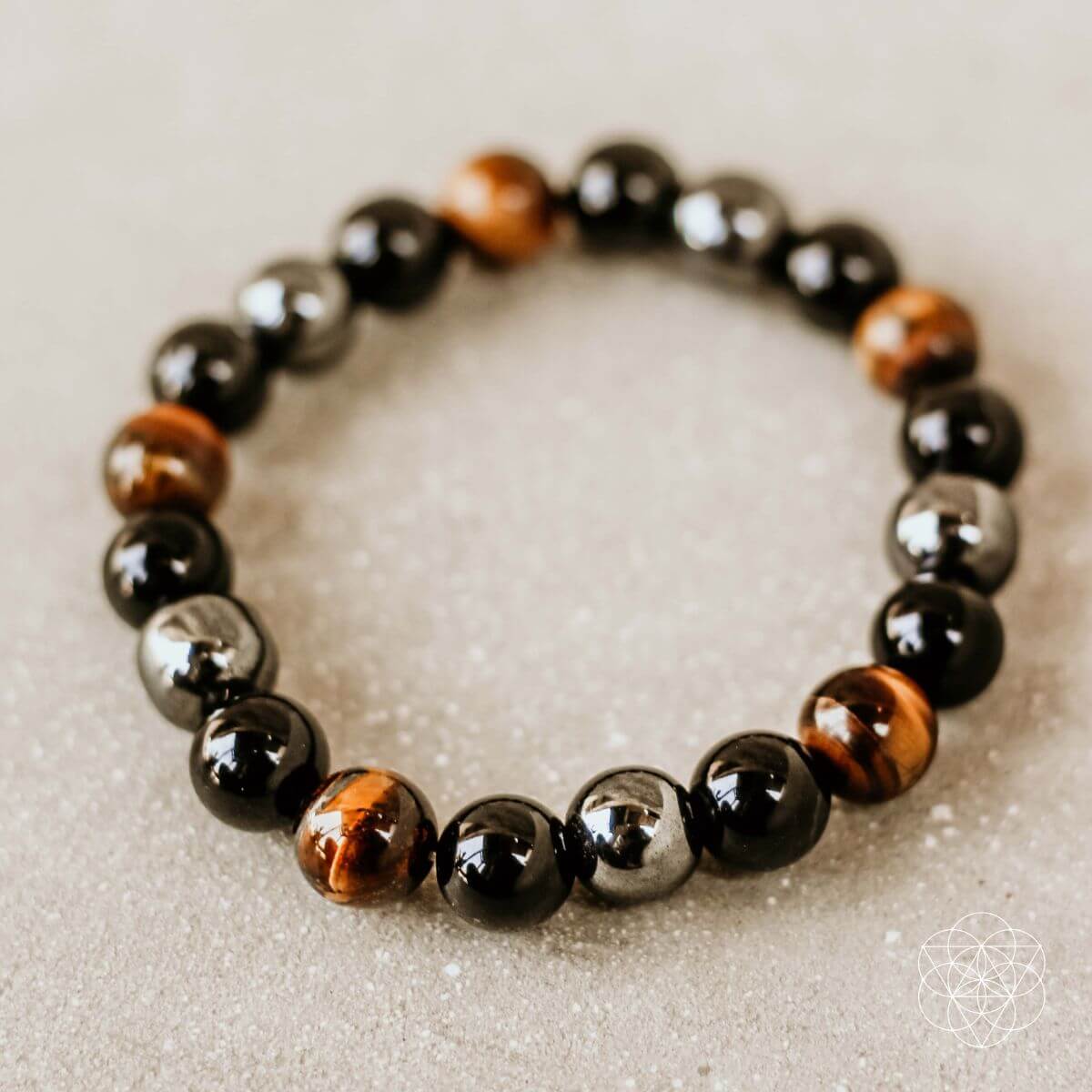 Beaded bracelet with black, brown, and silver beads on a light background